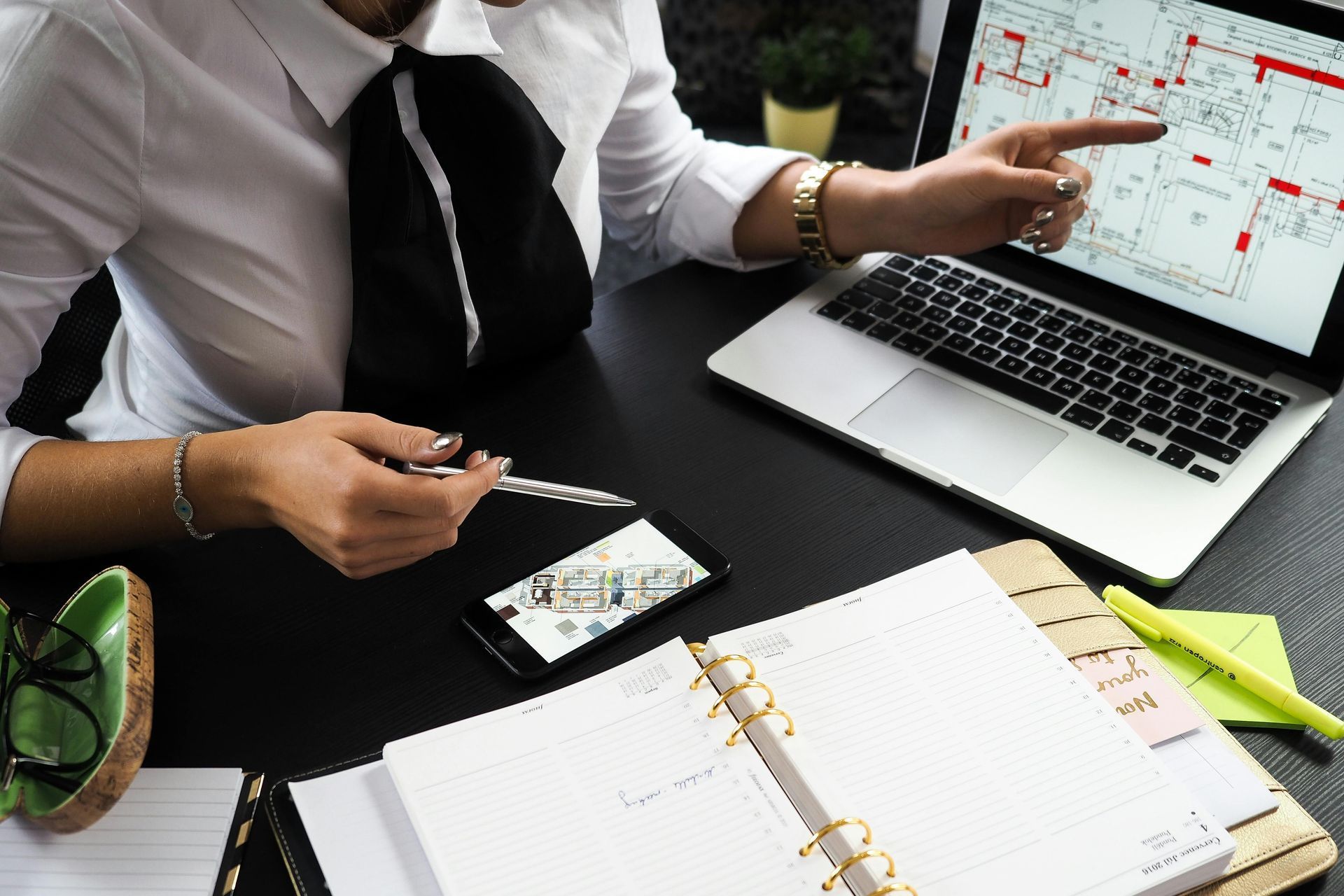 A man is sitting at a desk with a laptop and a cell phone.