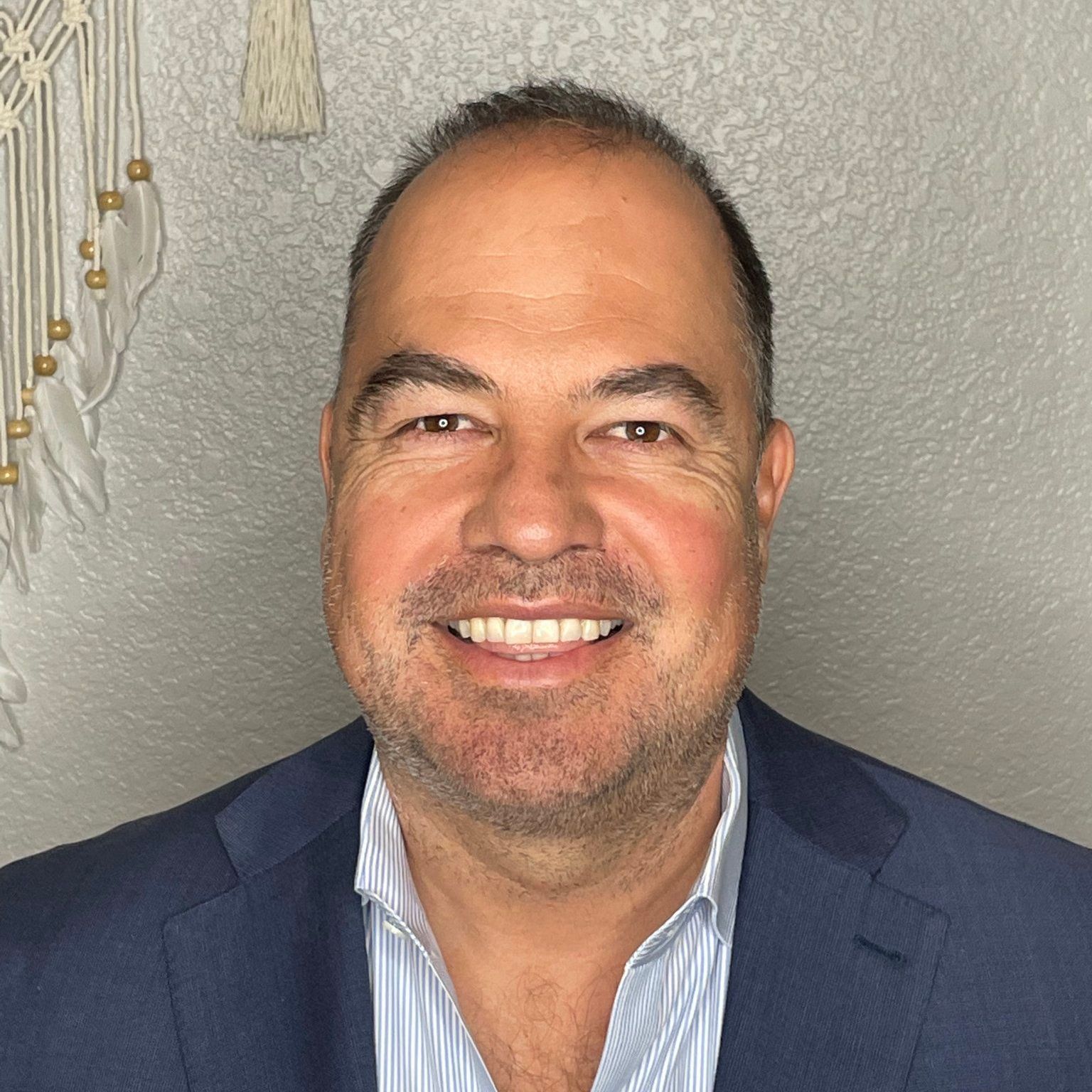 A man in a suit and striped shirt is smiling for the camera.