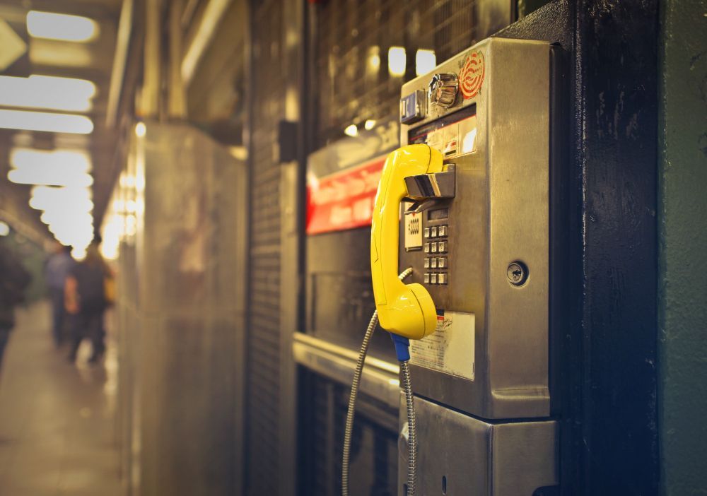Telefone público amarelo em uma estação de metrô mal iluminada.