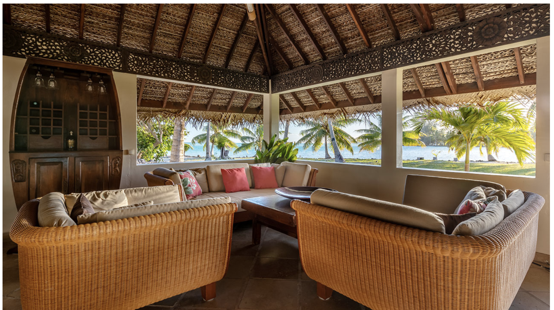 A living room with wicker furniture and a thatched roof.