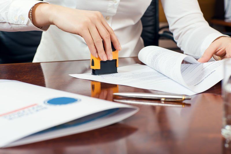A woman is stamping a piece of paper on a table.