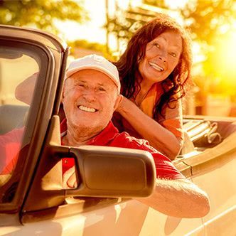A man and a woman are sitting in a car and smiling.
