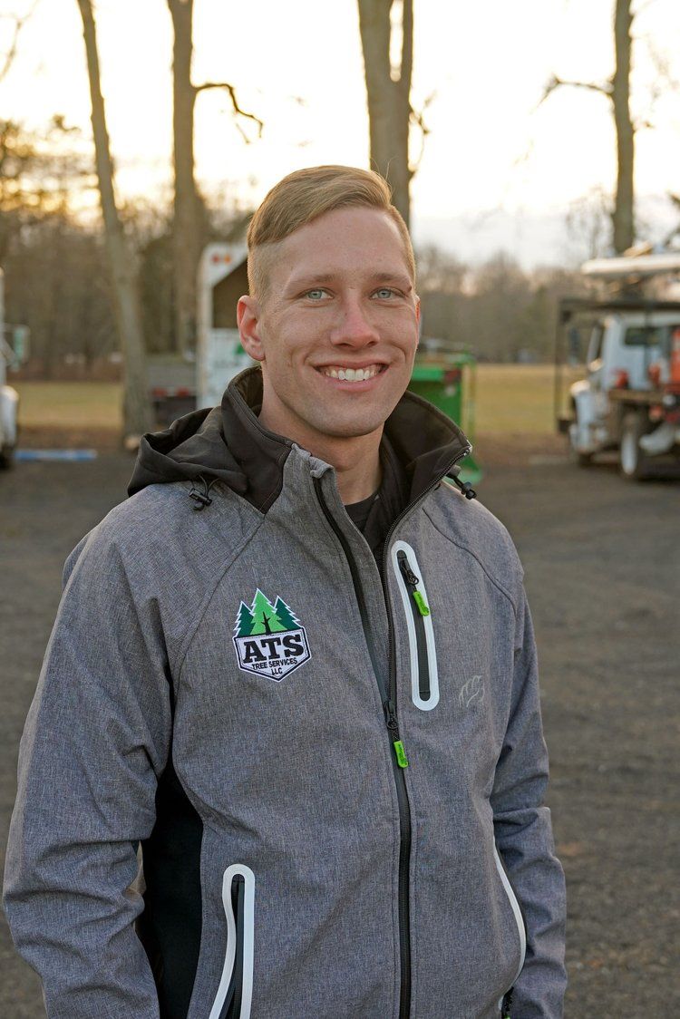 A man in a gray jacket is smiling in a parking lot.
