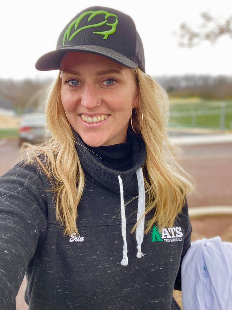 A woman wearing a hat and a hoodie is smiling for the camera.