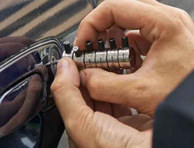 a locksmith is opening a car door with a tool .