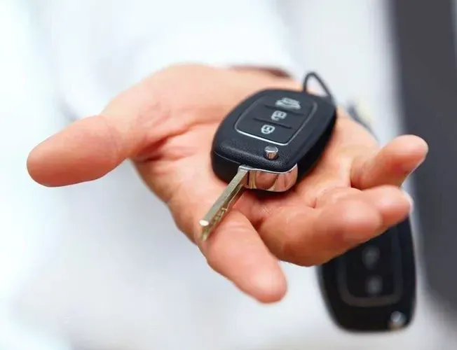 a locksmith is holding a car key in their hand .