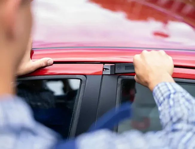 A man is opening the door of a red car.