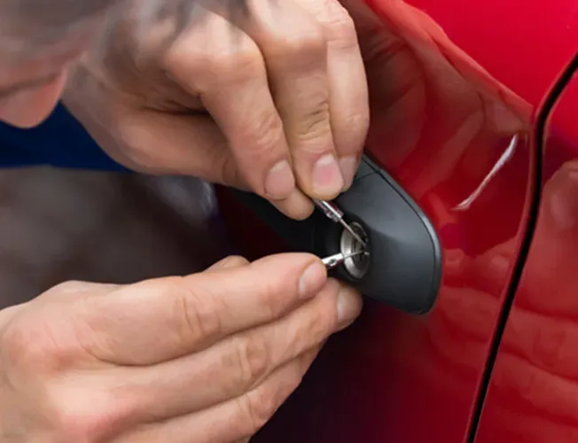 A man is using a screwdriver to open a car door.