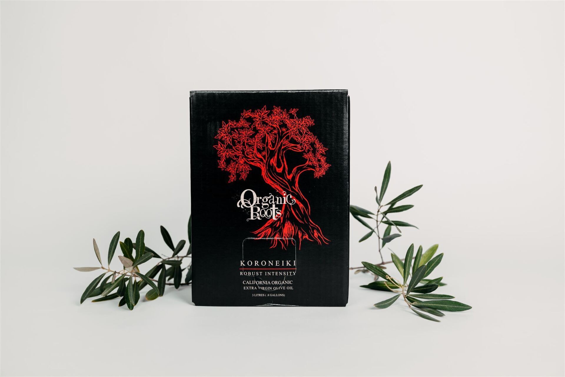 A black box with a red tree on it is surrounded by green leaves.