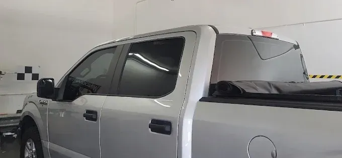 Silver pickup truck with tinted windows and a black tonneau cover.