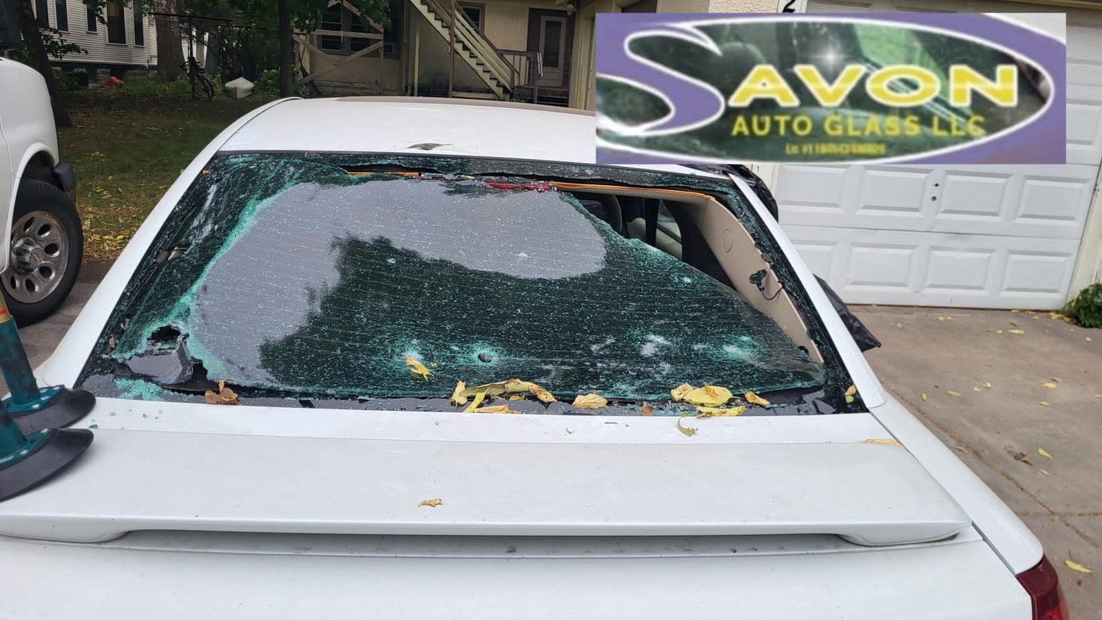 White car with shattered rear windshield, near a garage. Avon Auto Glass logo overlayed.