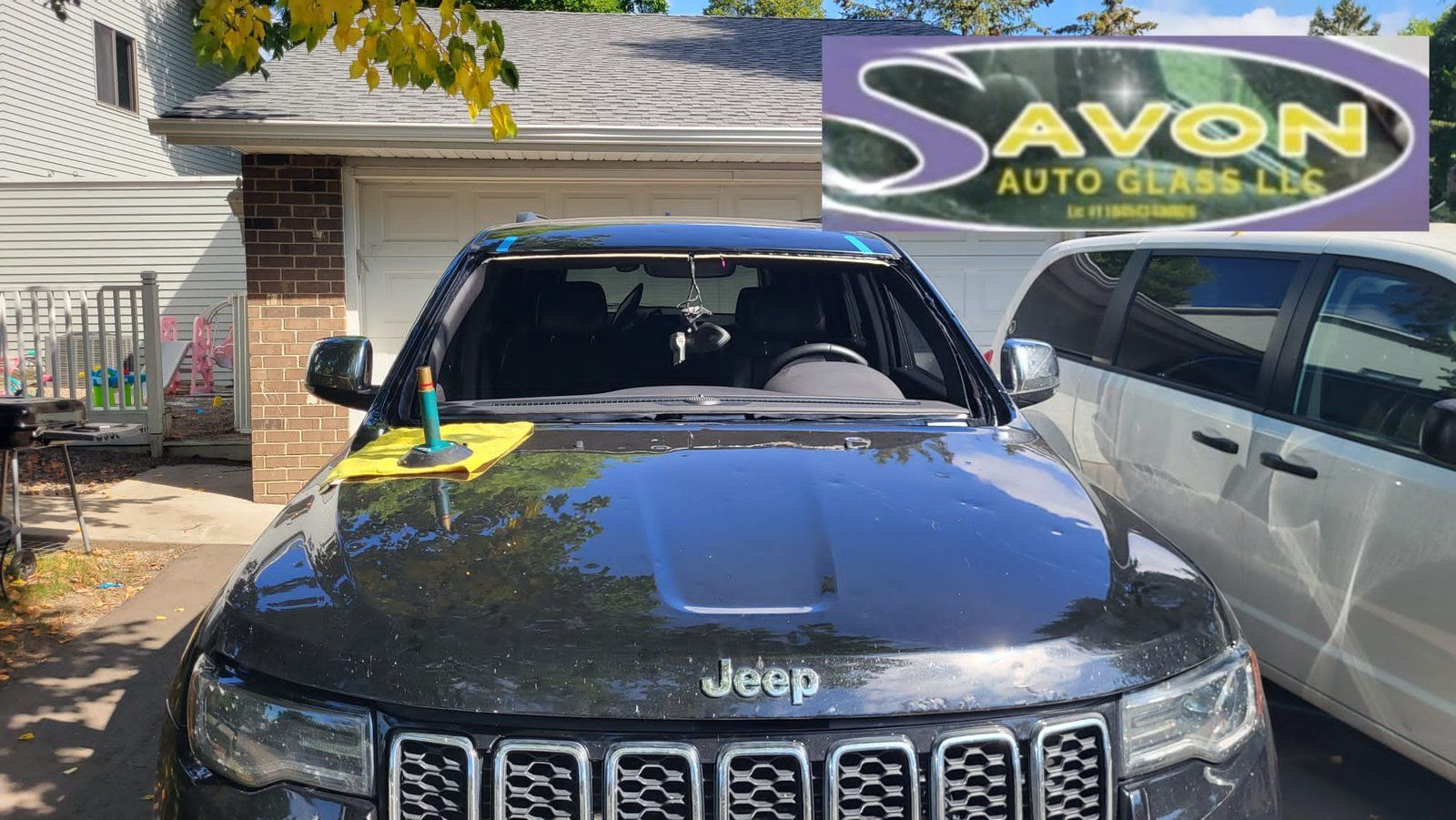 Black Jeep being worked on with glass replacement. Savon Auto Glass logo in corner.