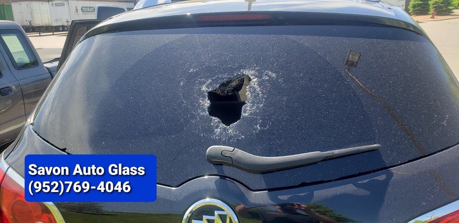 Black car rear window with a hole in it, with Savon Auto Glass contact info.