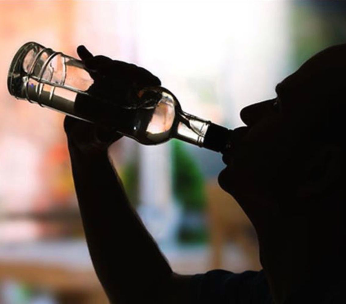 Man in shadow drinking from bottle