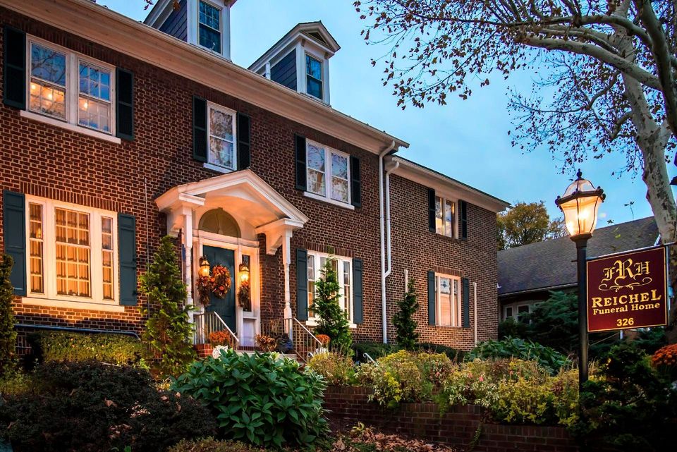 Brick hotel at dusk with lit windows, a porch entrance, and a sign reading “Auberge Michel.”