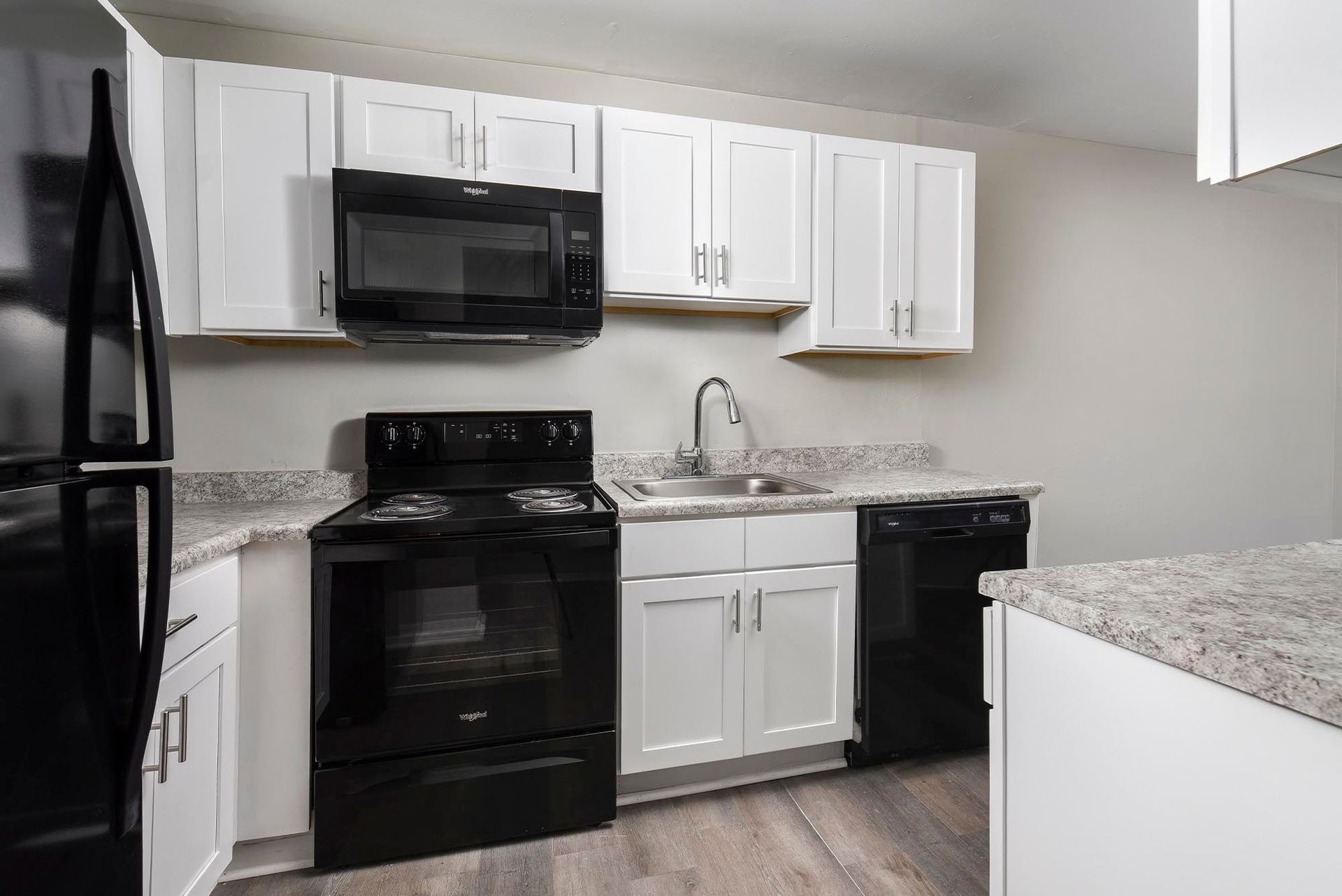 Kitchen with white cabinets, black appliances, and a double-basin sink at Chesapeake Pointe, offers Apartments for Rent in Chesapeake, VA.