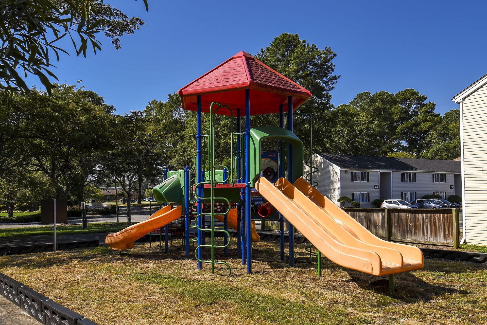 Colorful outdoor playground with slides and climbing structure beside apartment buildings at Chesapeake Pointe, offers  pet-friendly apartments in Chesapeake, VA