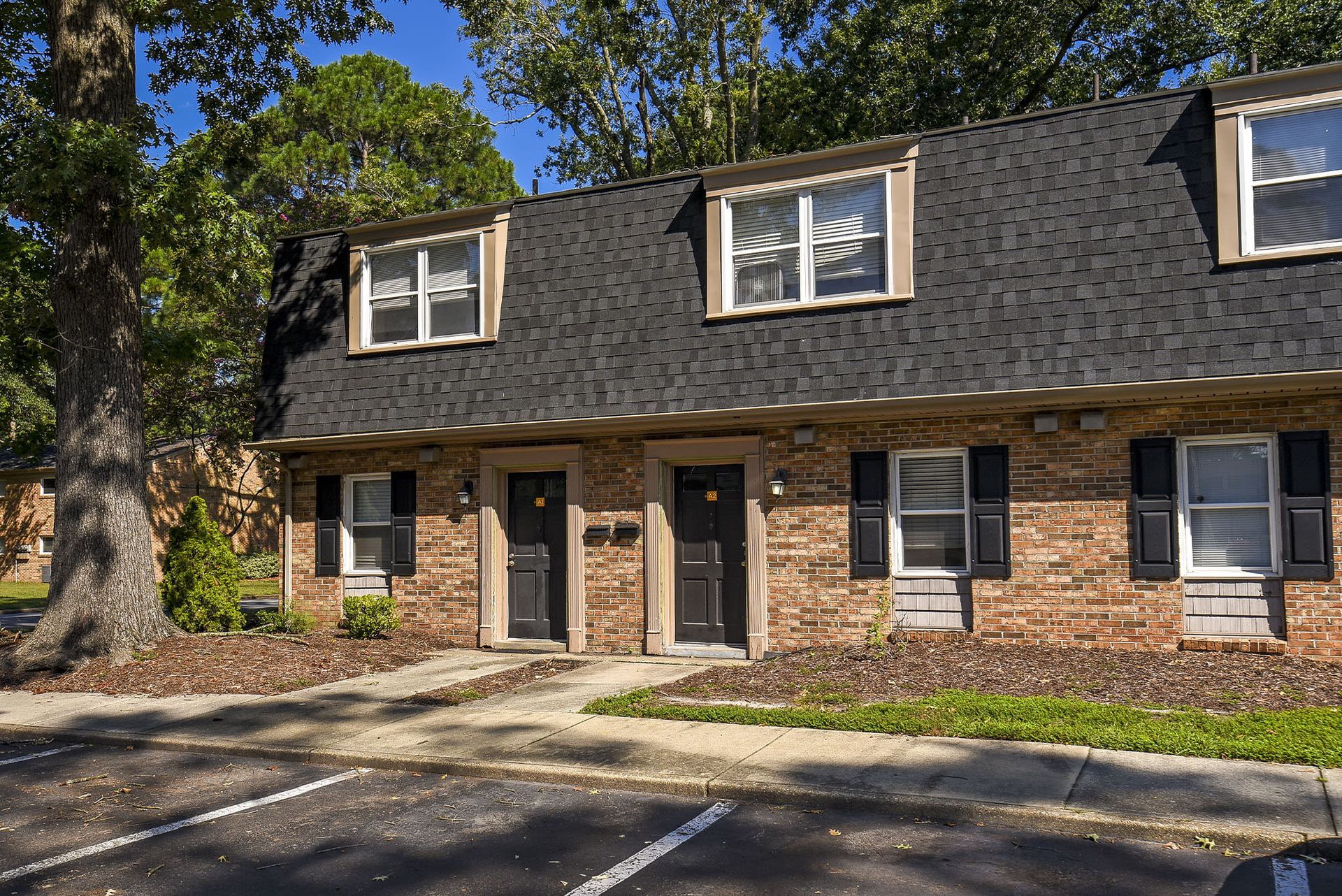 Exterior view of a brick multifamily building with individual entrances and black shutters at Chesapeake Pointe, offers  pet-friendly apartments in Chesapeake, VA