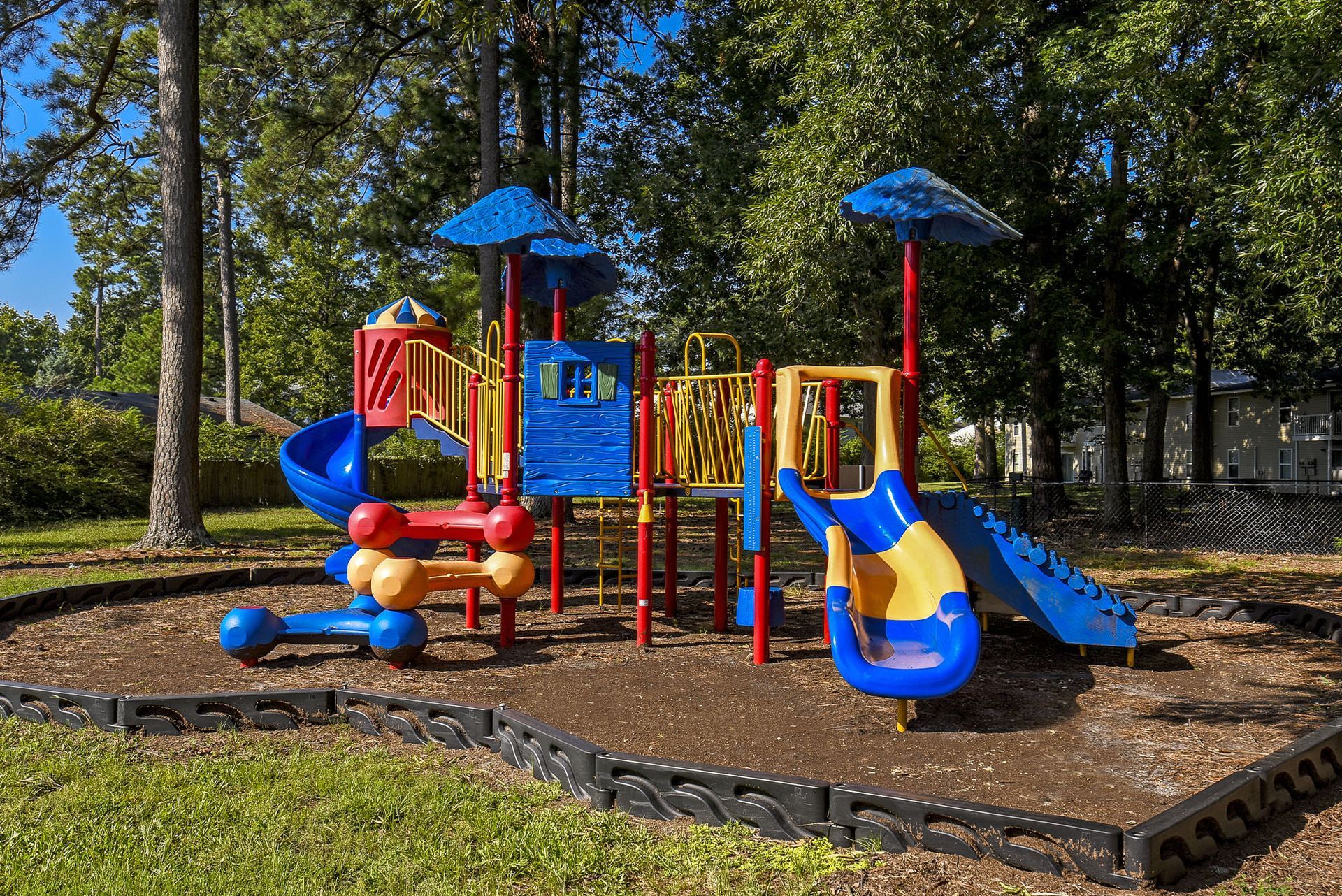 Colorful outdoor playground with slides and climbing structures in a shaded area at Chesapeake Pointe, offers  pet-friendly apartments in Chesapeake, VA