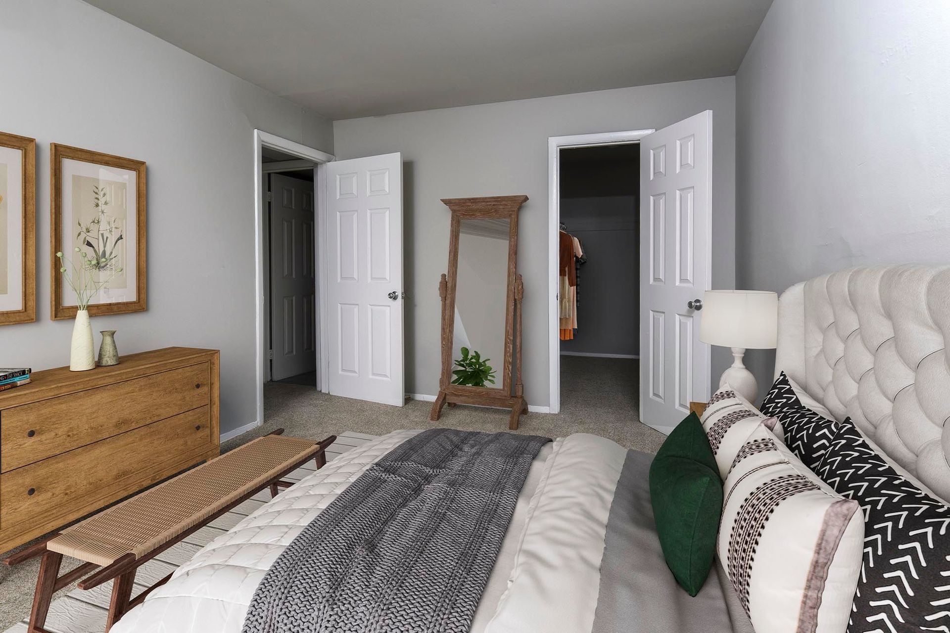 Bedroom with a tufted headboard, dresser, bench, and open closet doors at Chesapeake Pointe, offers Chesapeake, VA apartments for rent.