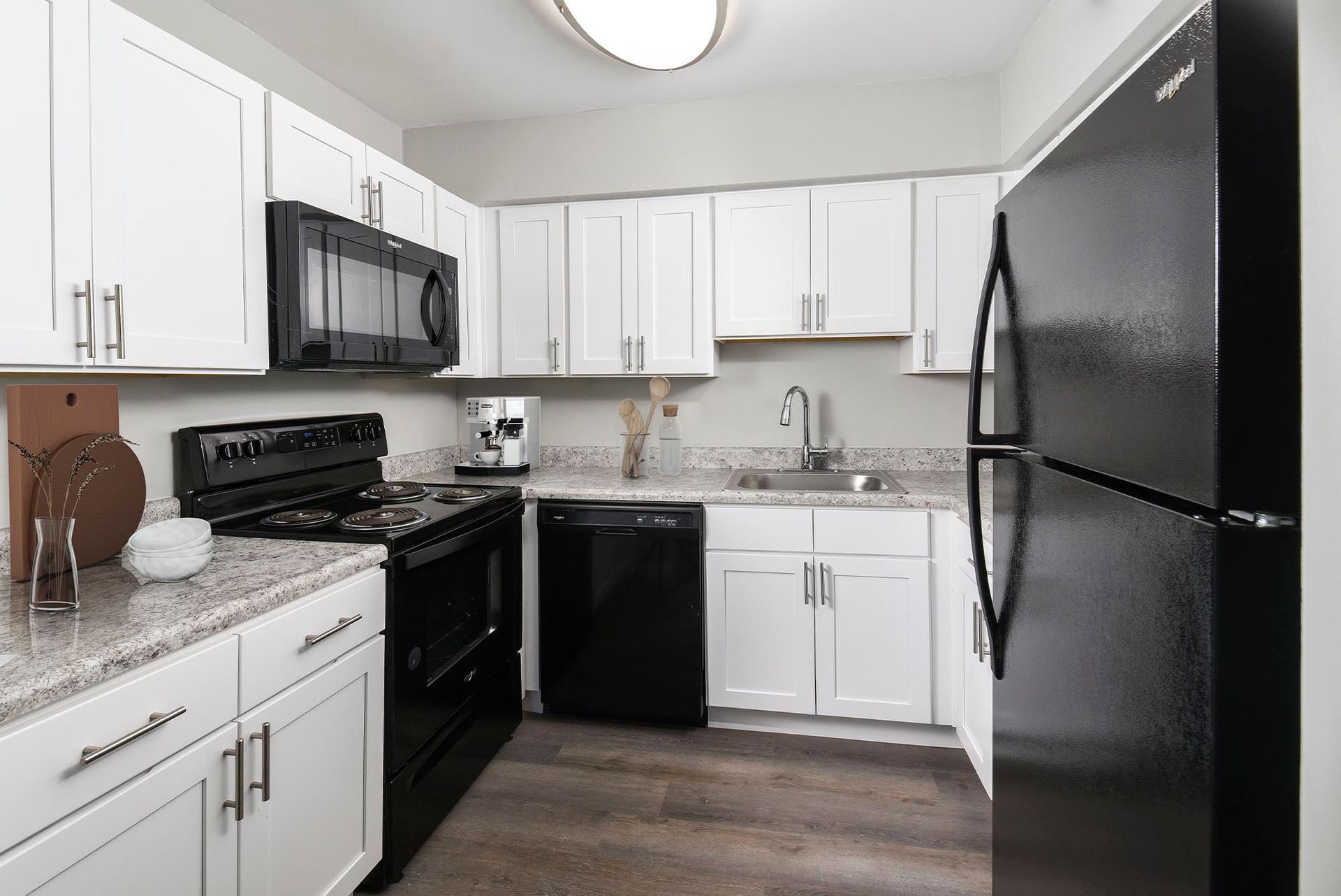 White kitchen with black appliances (stove, microwave, fridge) and granite countertops at Chesapeake Pointe, offers apartments in Chesapeake, VA.