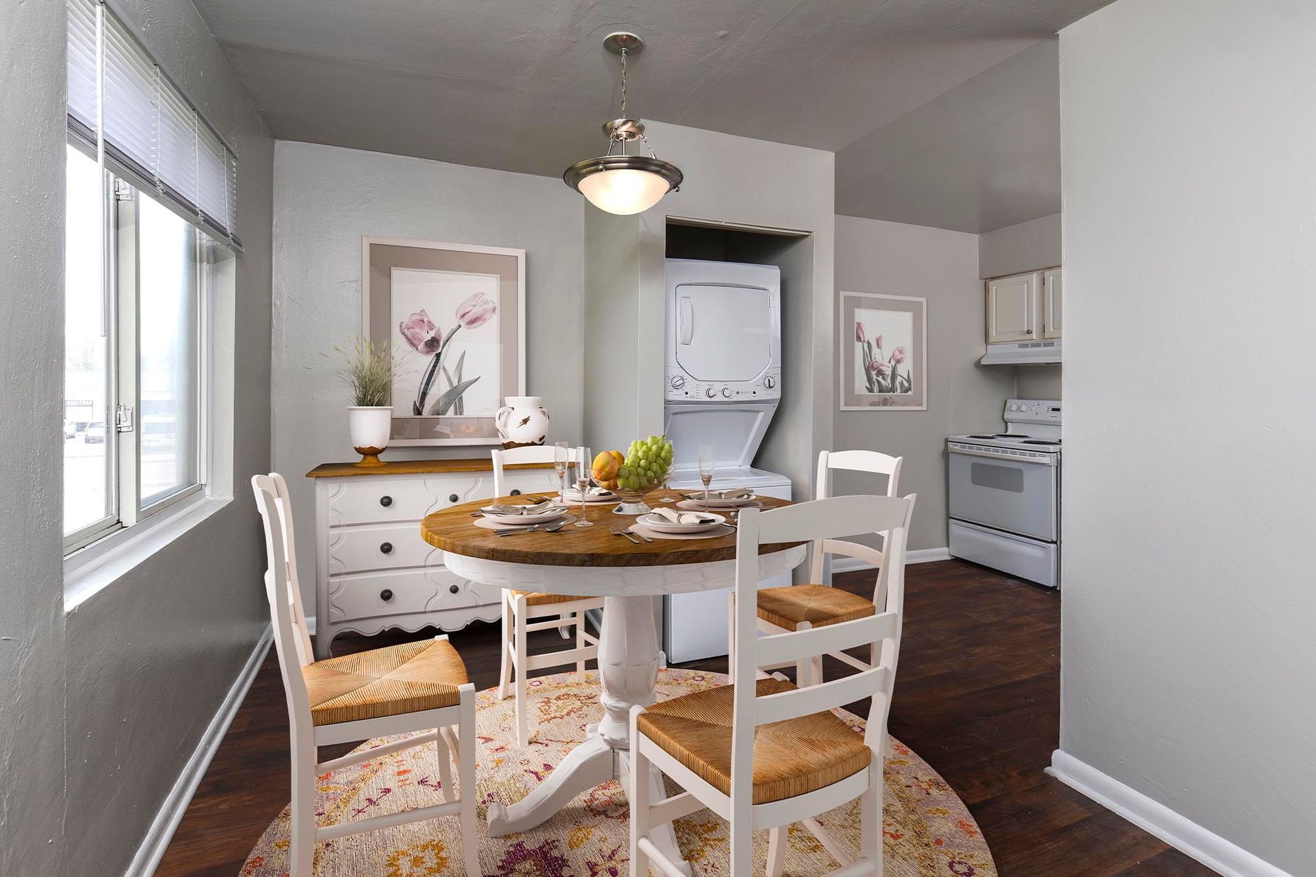 Dining nook with round wooden table, four white chairs, and a washer/dryer in the adjacent kitchen at Chesapeake Pointe, offers apartments in Chesapeake, VA.