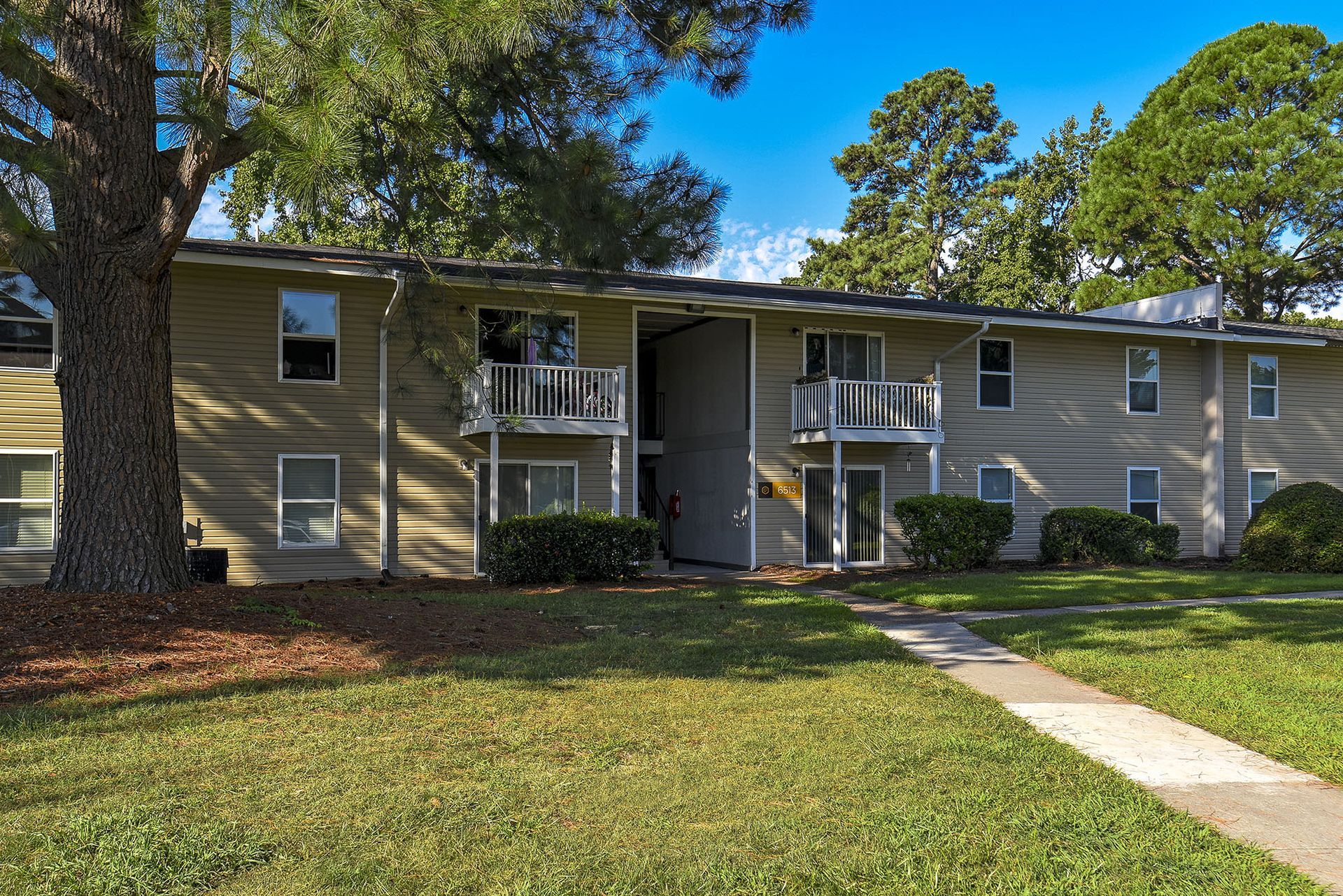 Exterior view of a two-story apartment building with balconies and a grassy lawn at Chesapeake Pointe, offers  pet-friendly apartments in Chesapeake, VA