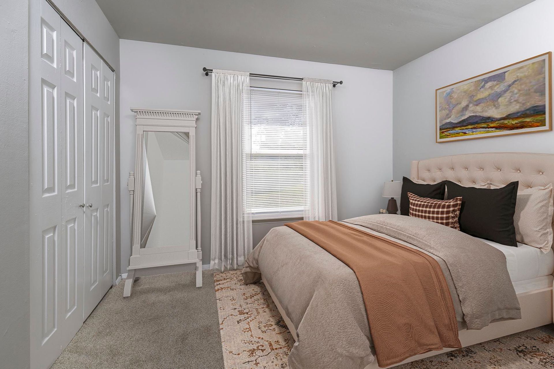Bedroom in an apartment with a queen bed, window with sheer curtains, and a white dresser with a mirror at Chesapeake Pointe, offers apartments in Chesapeake, VA.