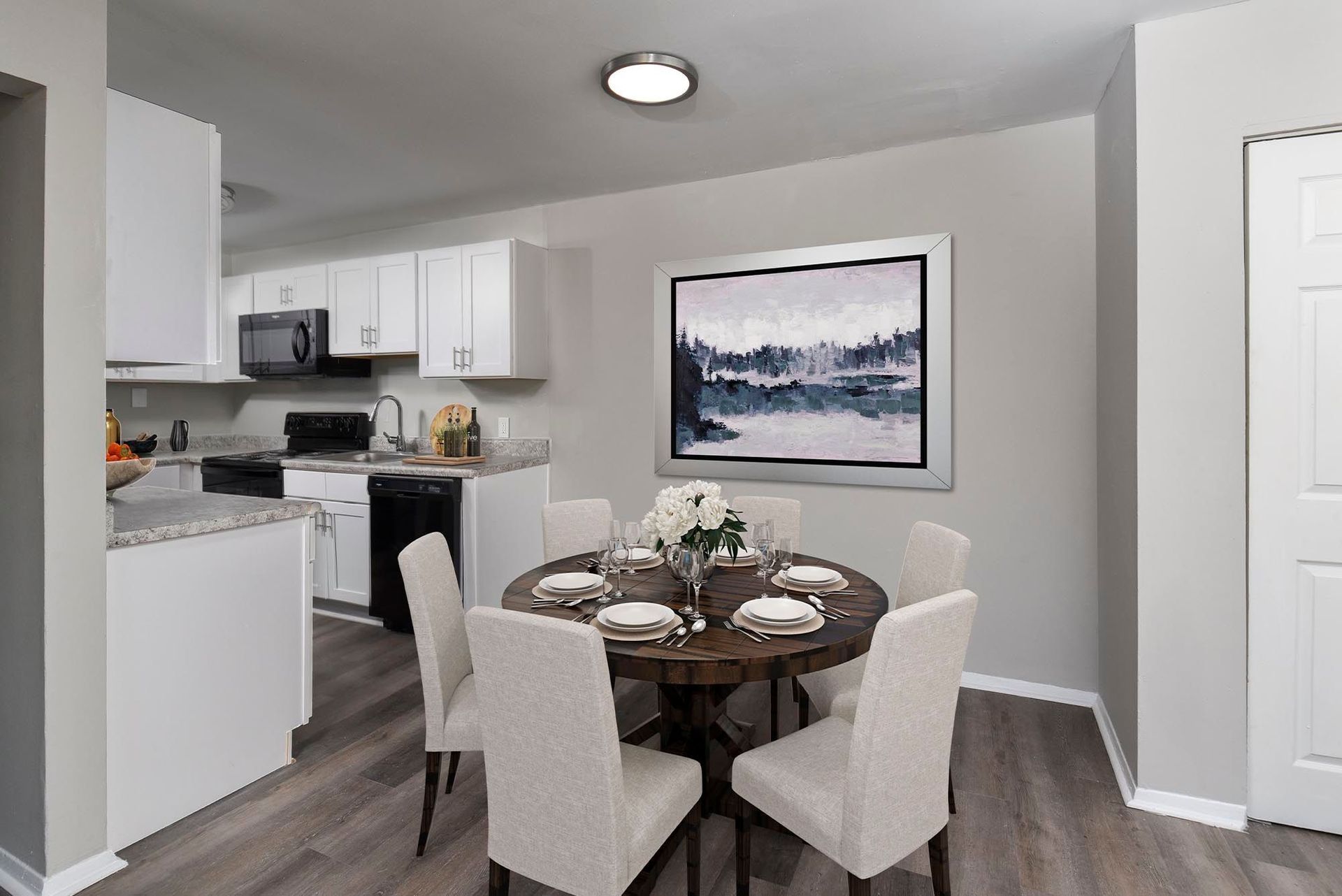 Interior view of an apartment kitchen and dining area with white cabinets and a round wooden table at Chesapeake Pointe, offers Apartments for Rent in Chesapeake, VA.