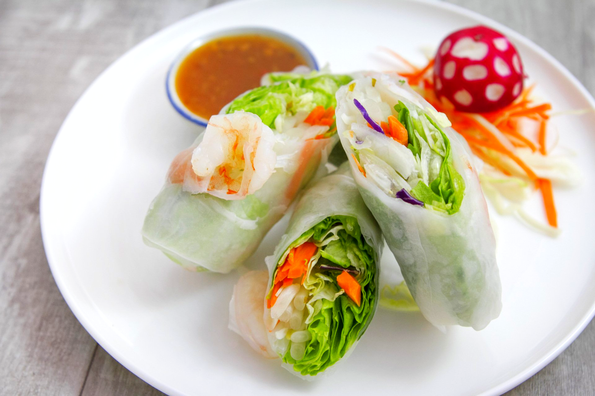 A white plate topped with vegetable rolls and a dipping sauce.