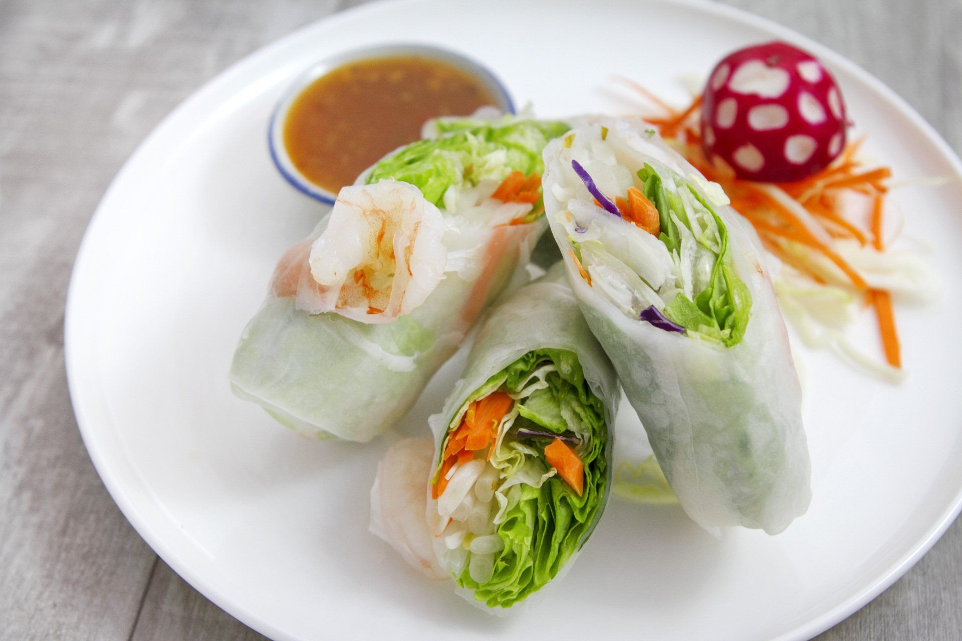 A white plate topped with vegetable rolls and a dipping sauce.