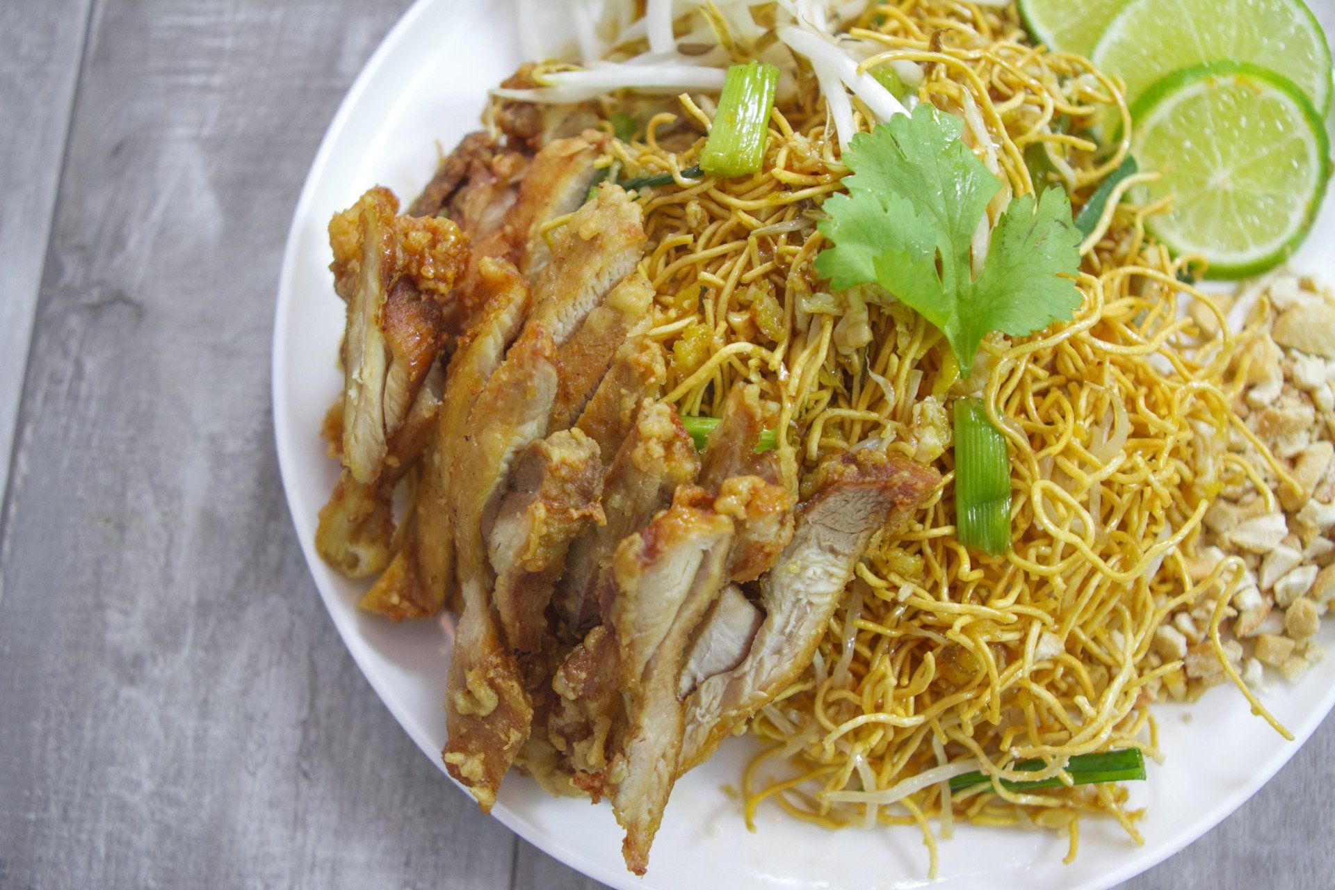 A white plate topped with noodles , meat and vegetables.