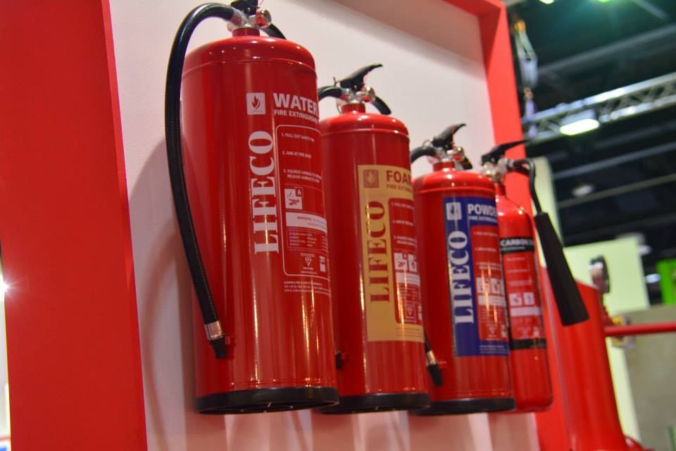 Extincteurs rouges de différents types montés sur un mur.