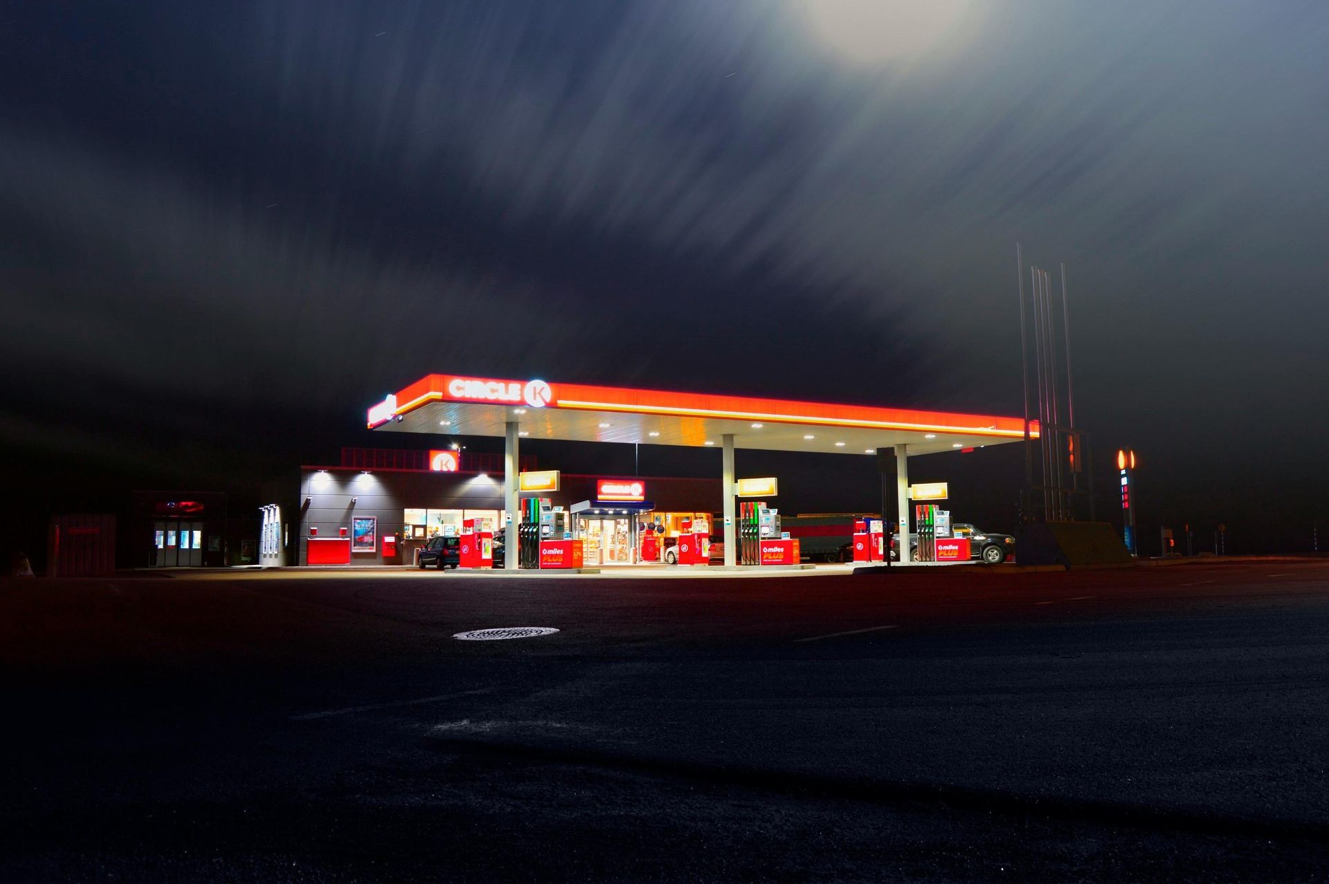 Une station-service Circle K brillamment éclairée la nuit sous un ciel nuageux.