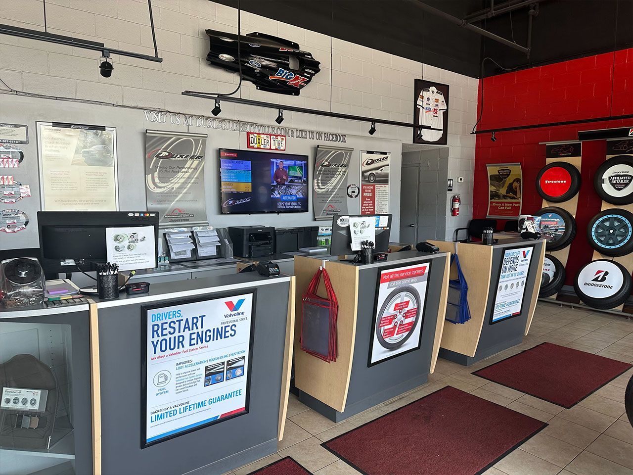 The inside of a tire shop named Duxler Libertyville with a sign that says `` restart your engine ''.