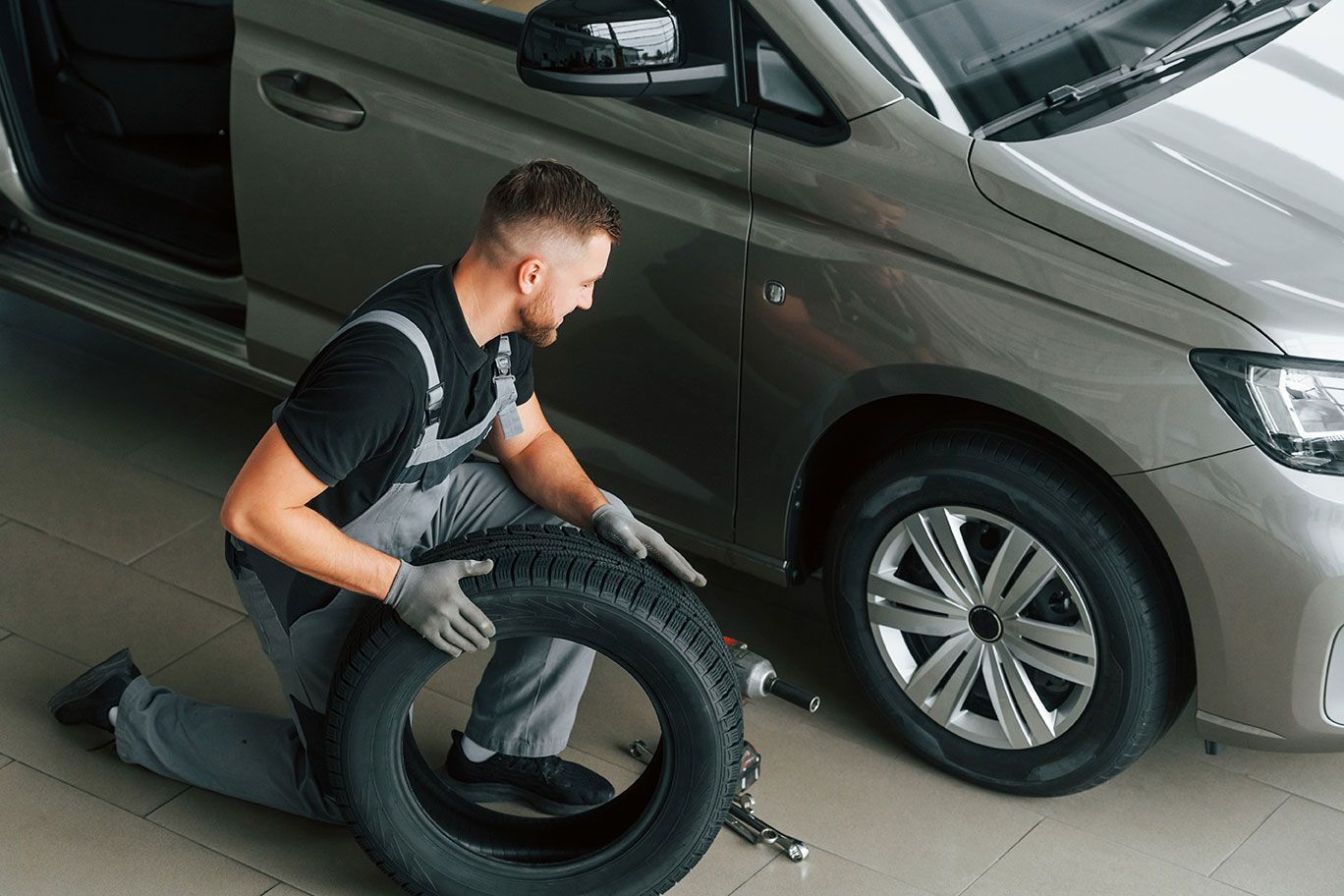 A man is changing a tire on a car in a garage.