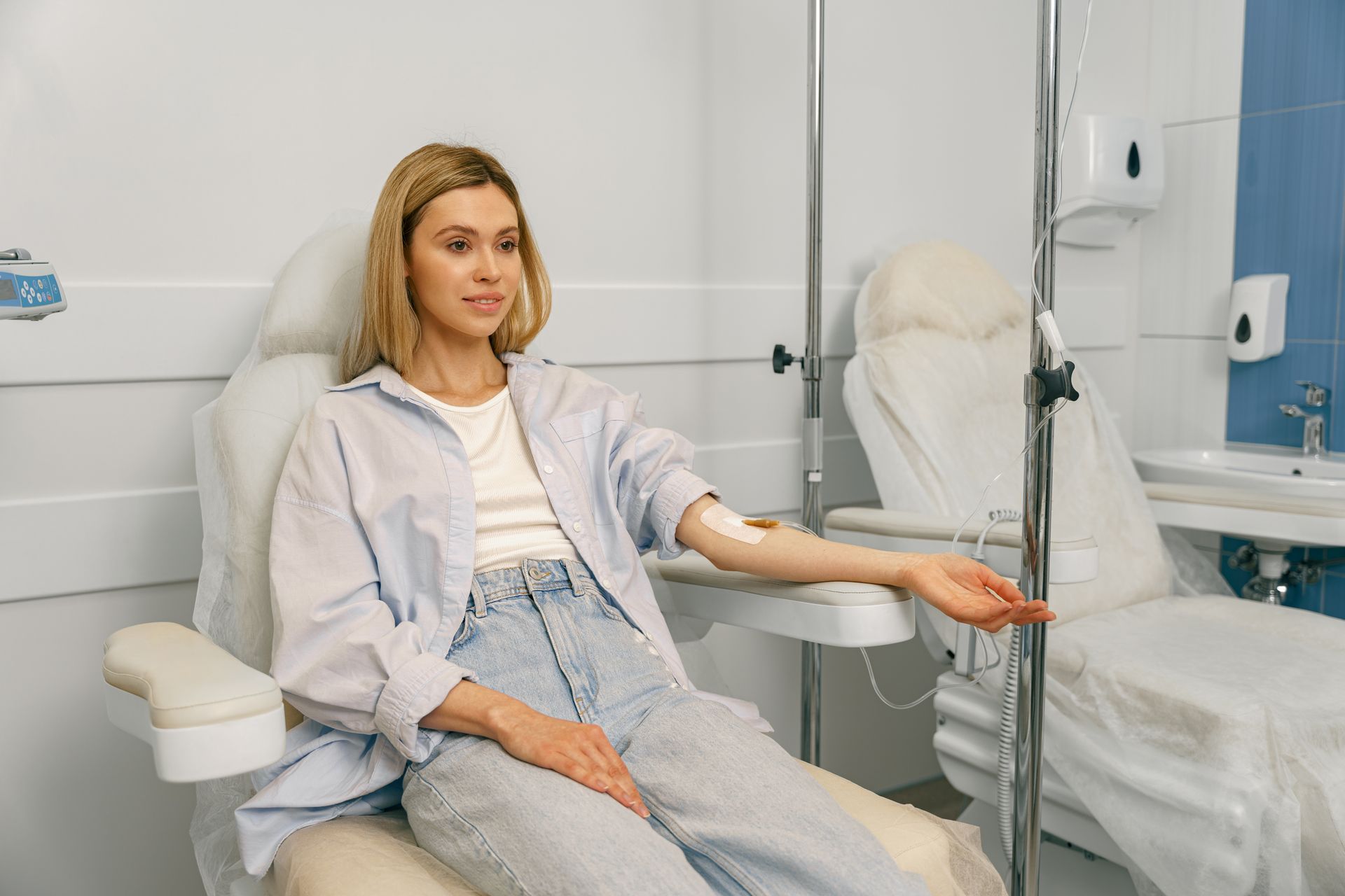 A woman is sitting in a hospital chair with an iv in her arm.