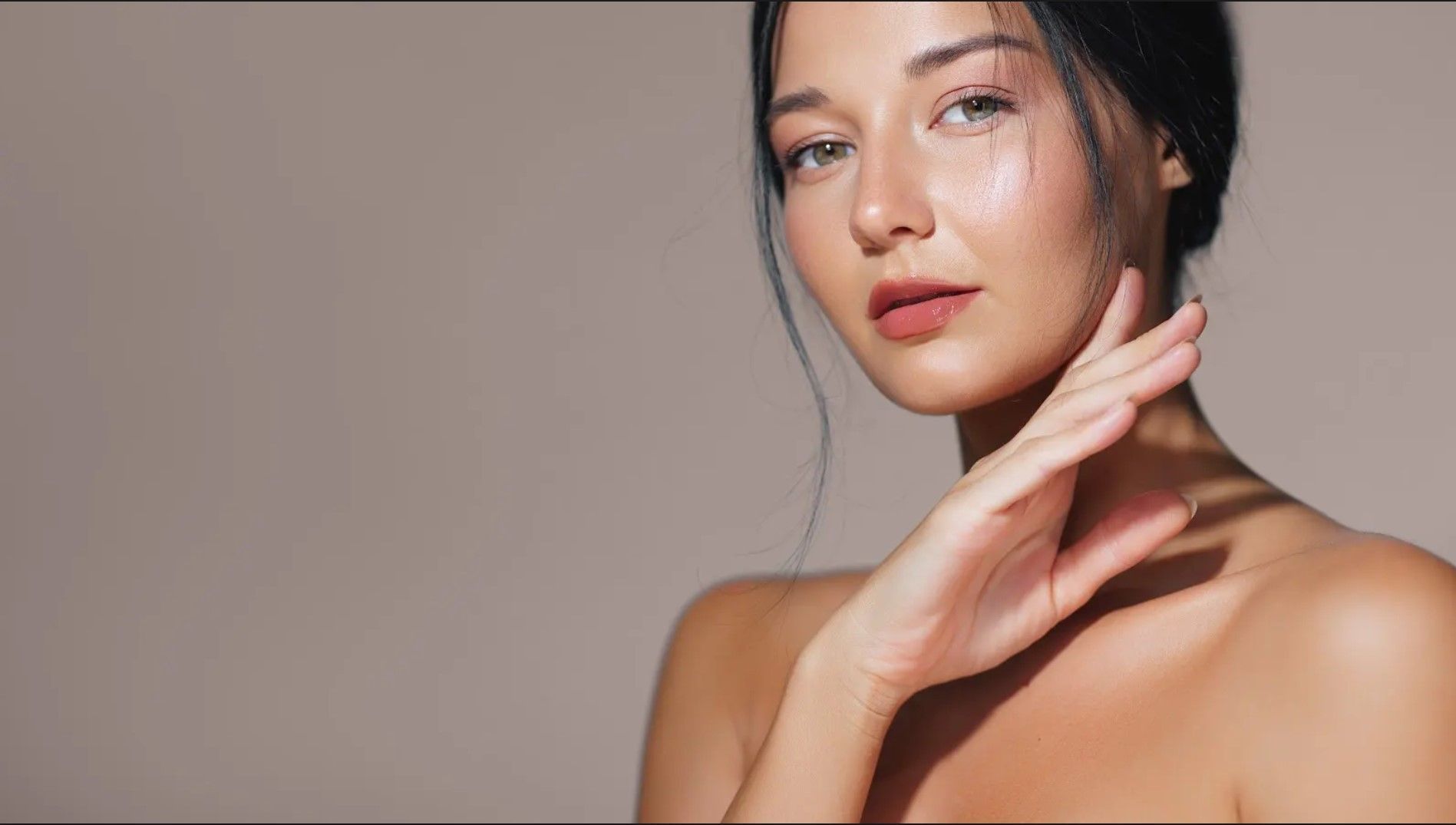 A woman is touching her face with her hand and looking at the camera.