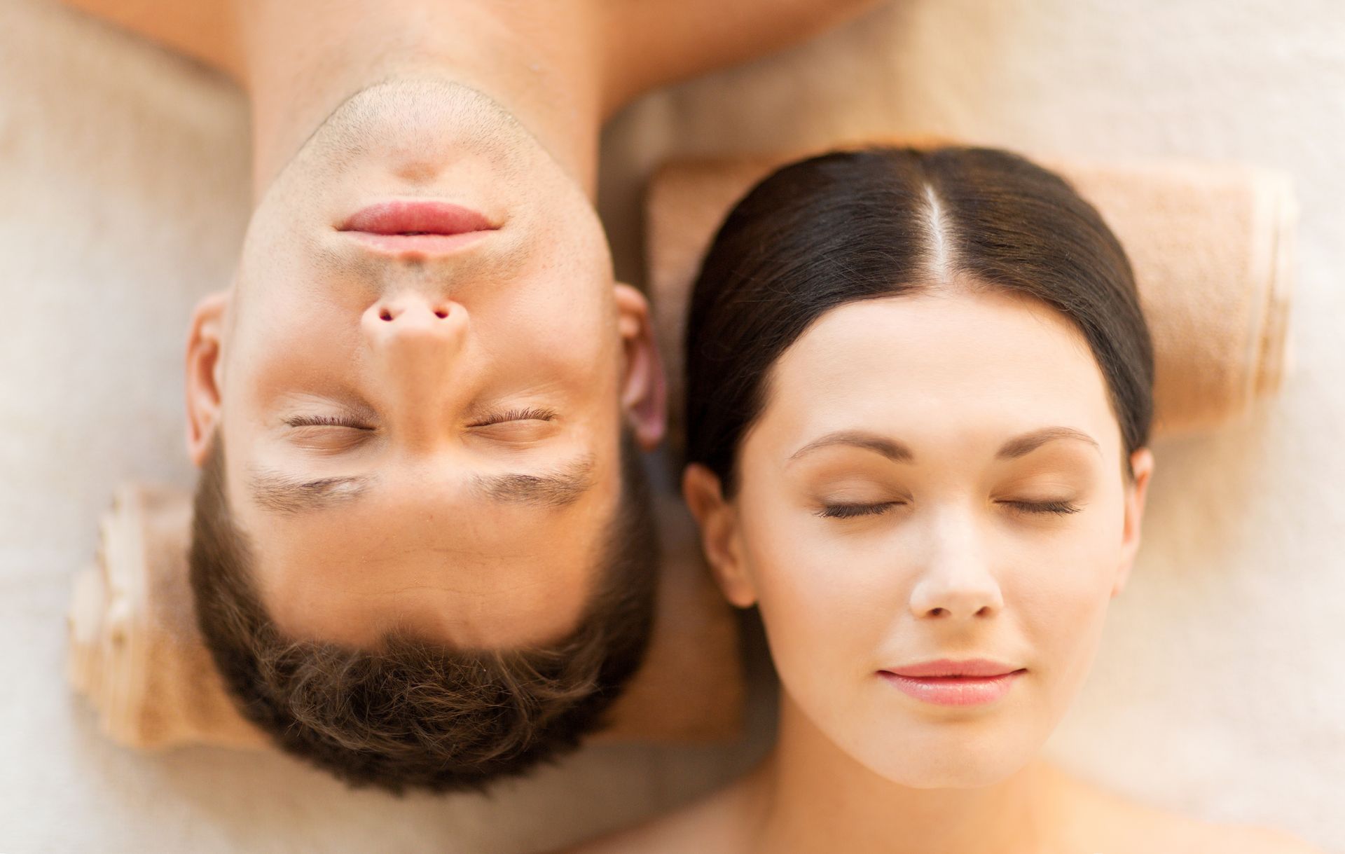 Couple with closed eyes resting on spa towels.