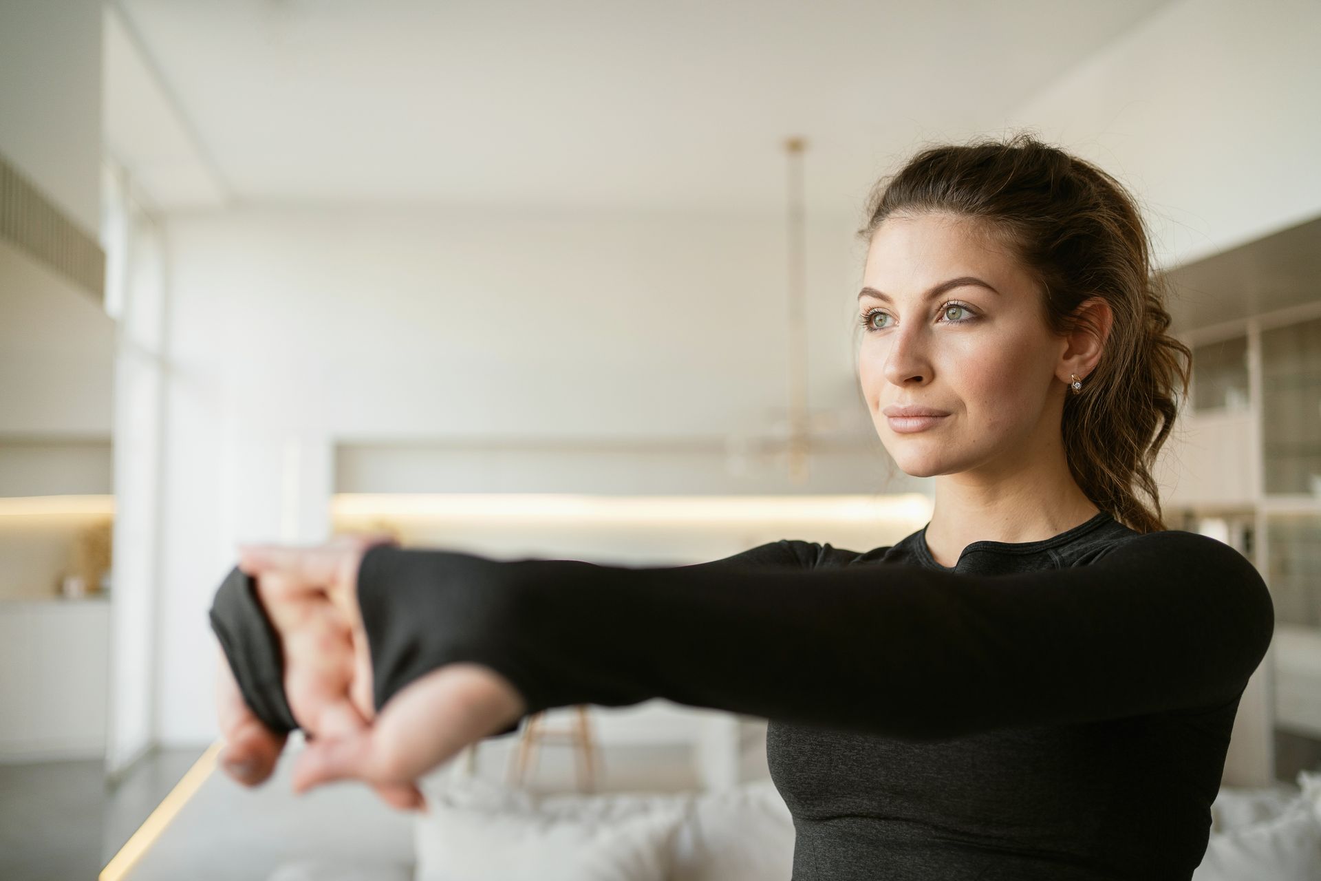 A woman is stretching her arms with a resistance band in a living room.