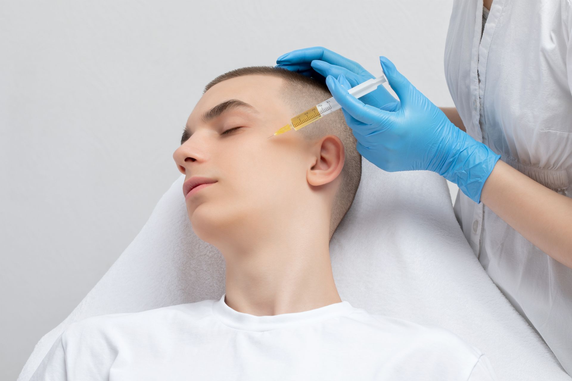 A young man is getting a botox injection in his face.