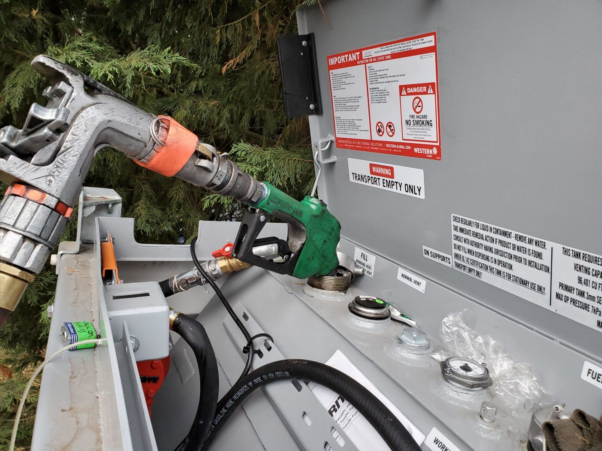 A gas pump is being filled with gas from a tank.