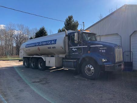 A large tanker truck is parked in front of a building.