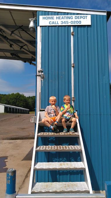 Two young boys are sitting on the steps of a blue building.