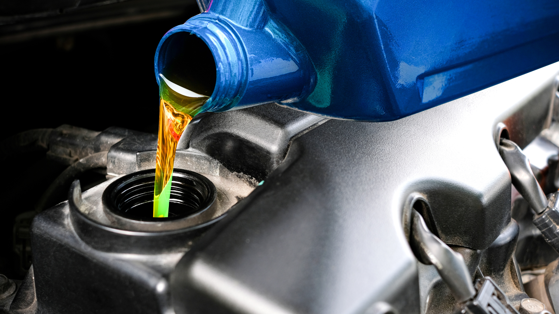 A bottle of oil is being poured into a car engine