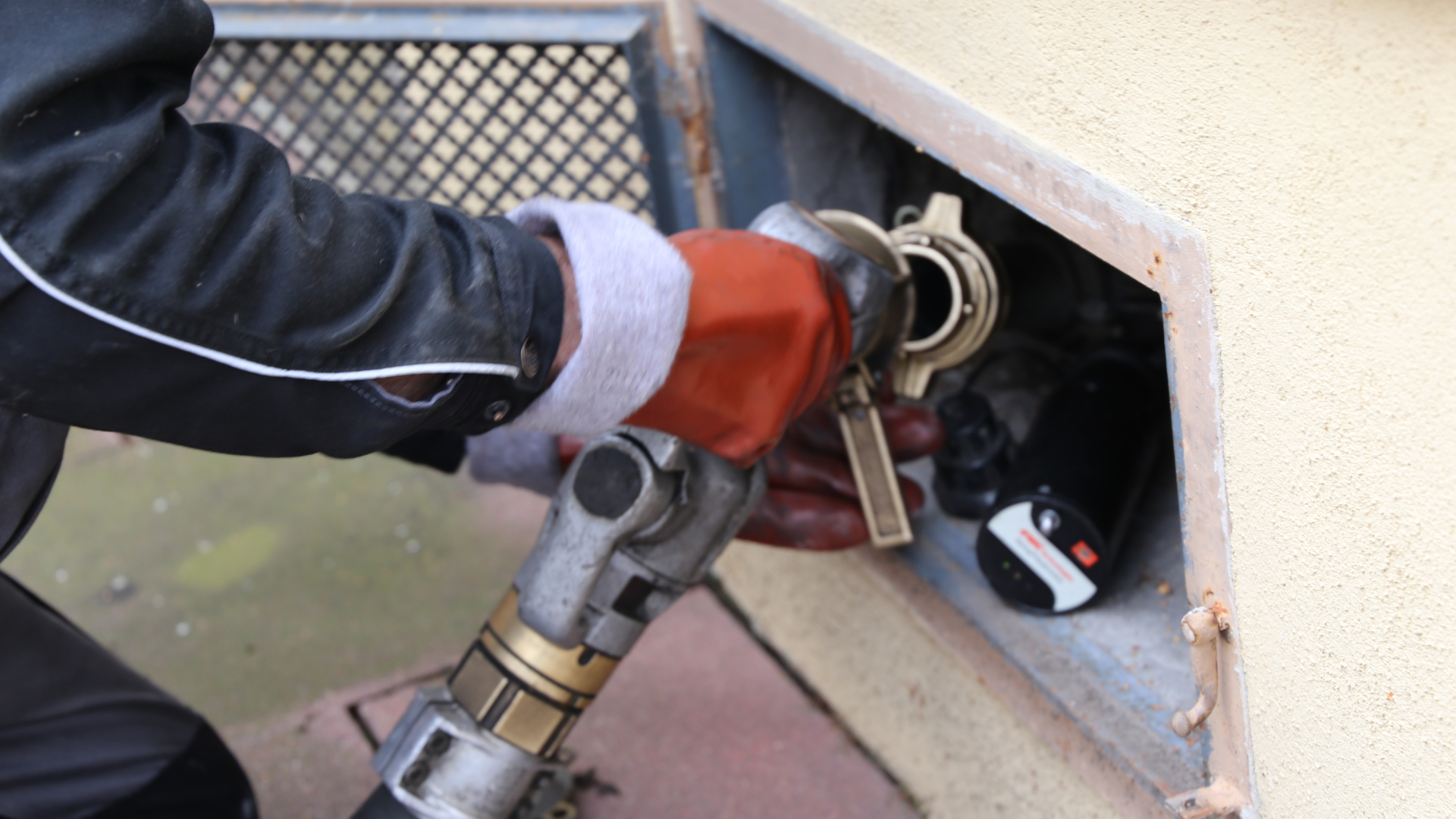 A person is using a hose to pump gas into a container.