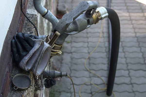 A hose is attached to a pipe on the side of a building.