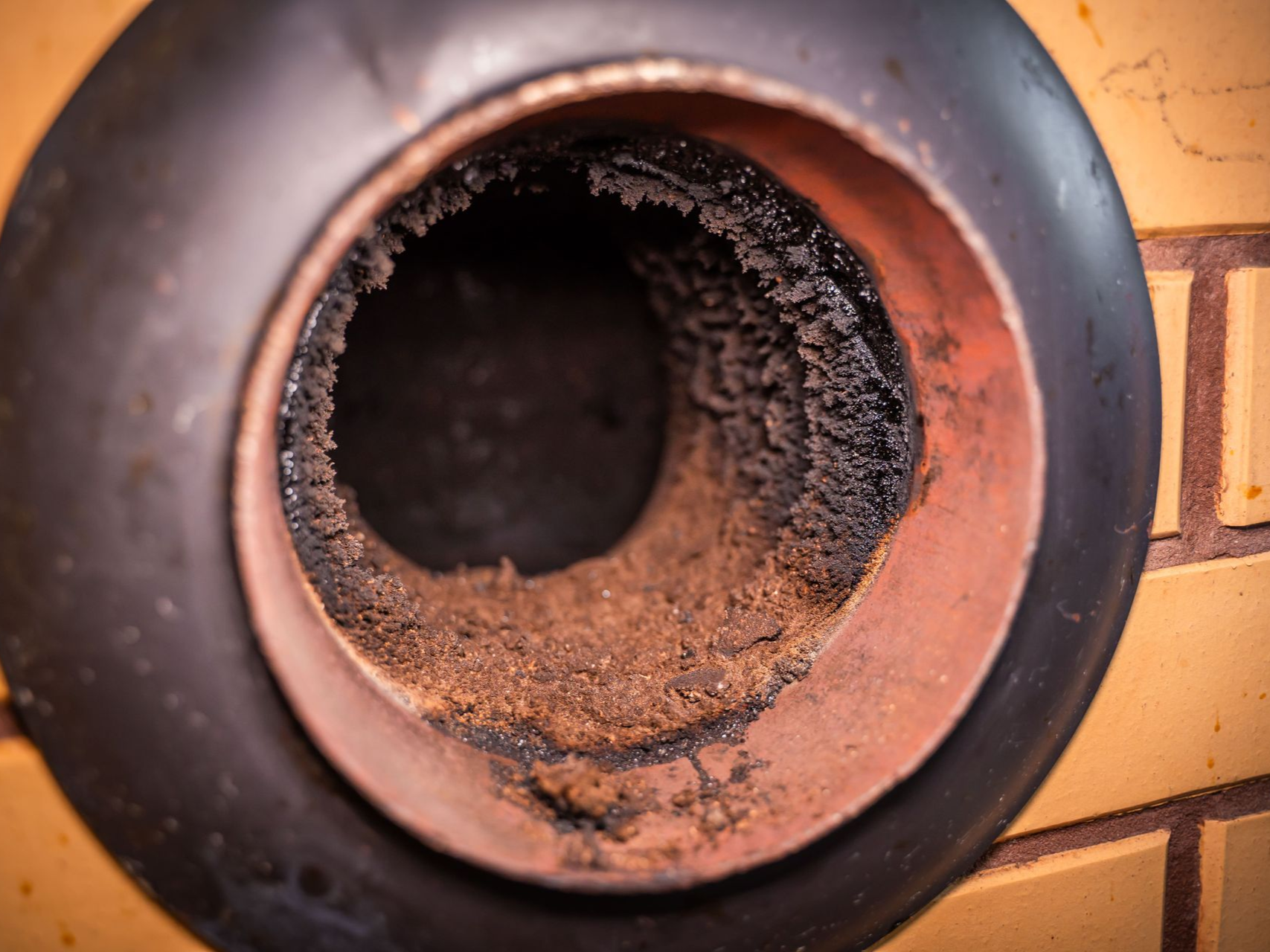 Close-up of a chimney flue, coated in thick, dark creosote with brick wall surround.
