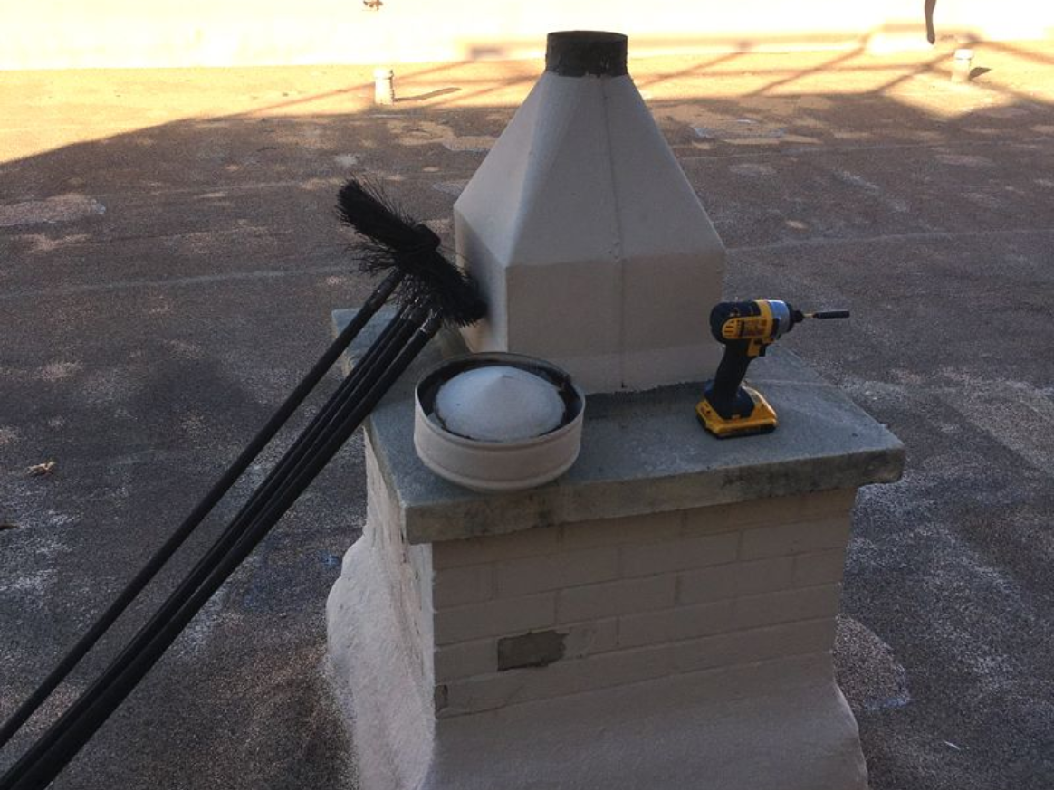 Chimney cleaning tools on a rooftop: brush, rods, cap, drill, and chimney.