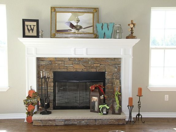 Fireplace with stone surround, decorated with candles, mirror, and a